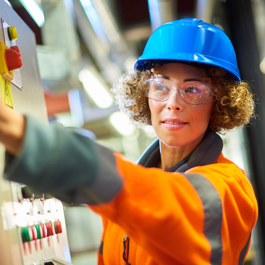 Frau mit blauem Helm vor Technikanlage